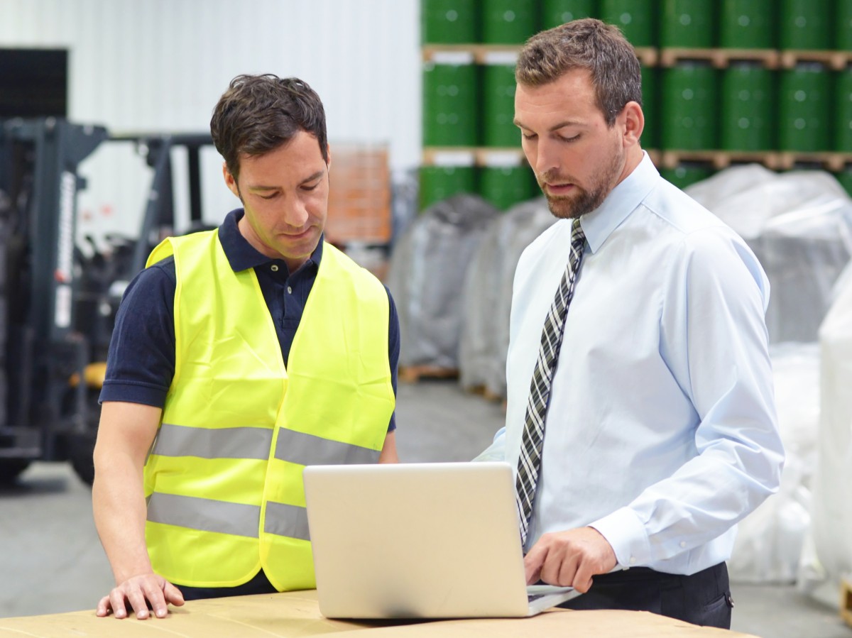 Geprüfter Fachwirt für Güterverkehr und Logistik unterweist einen Logistikmitarbeiter im Lager