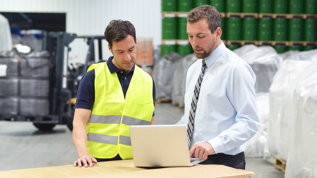 Geprüfter Fachwirt für Güterverkehr und Logistik unterweist einen Logistikmitarbeiter im Lager
