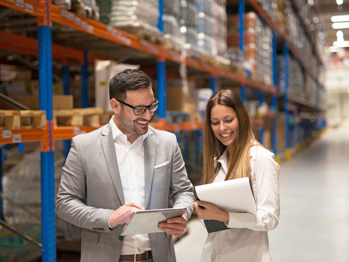 Geprüfte Fachwirte für Logistiksysteme (Mann und Frau) in großer Lagerhalle