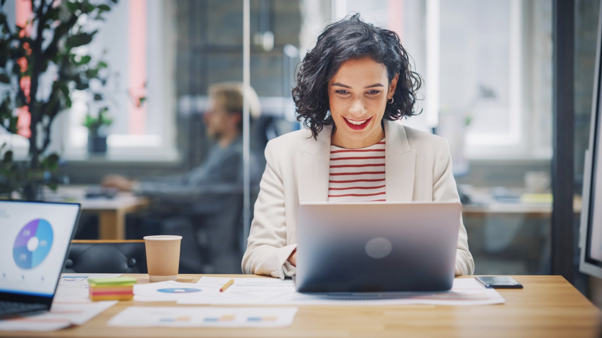 Geprüfte Fachwirtin für Marketing sitzt am Laptop und freut sich über den Erfolg der Marketing-Kampagne