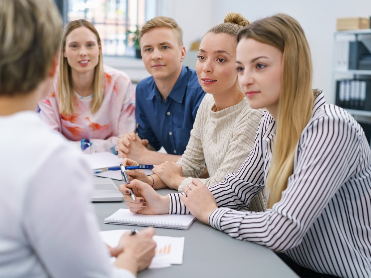 Auszubildende sitzen am Tisch mit Ausbilderin