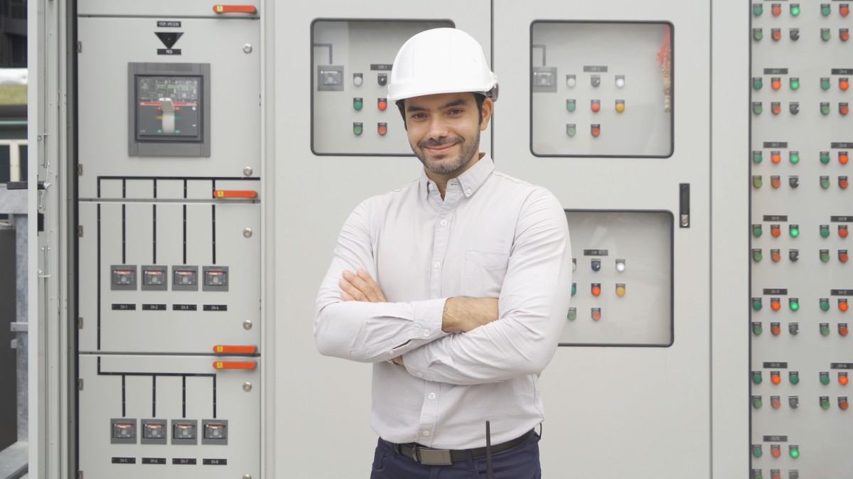 OGeprüfter Industriemeister Elektrotechnik steht vor Schaltschrank